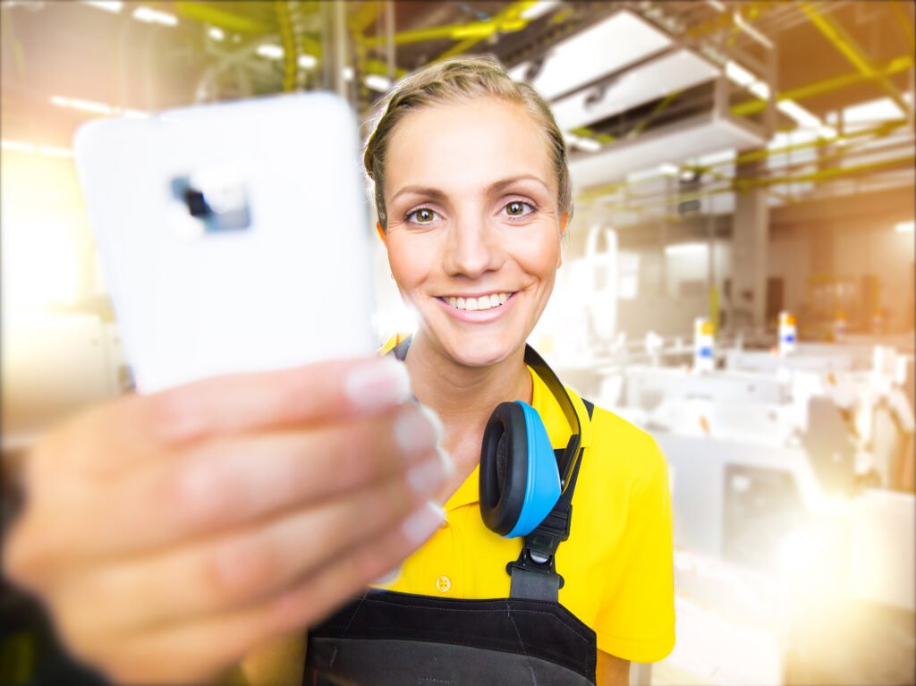 On-Location Recruiting-Visual — Fachkraft in Schutzausrüstung mit Tablet in Produktionshalle. Employer-Branding für Industri…